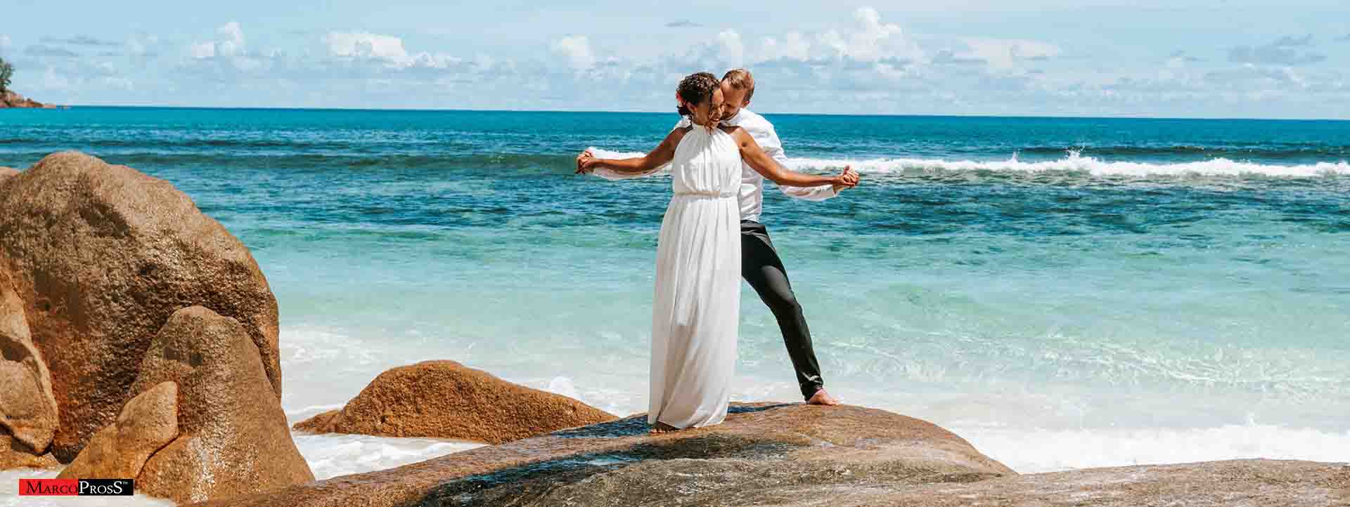 wedding couple holding on a beach stones - on Anse Bazarca beach - Seychelles
